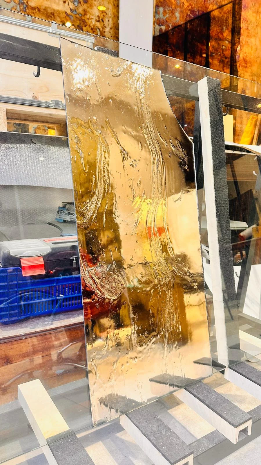 An amber reflective glass panel displayed in the workshop